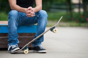 Man sit with skateboard.